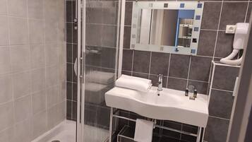 A modern bathroom with a glass-enclosed shower, a white sink with a mirror above it, and a toilet.