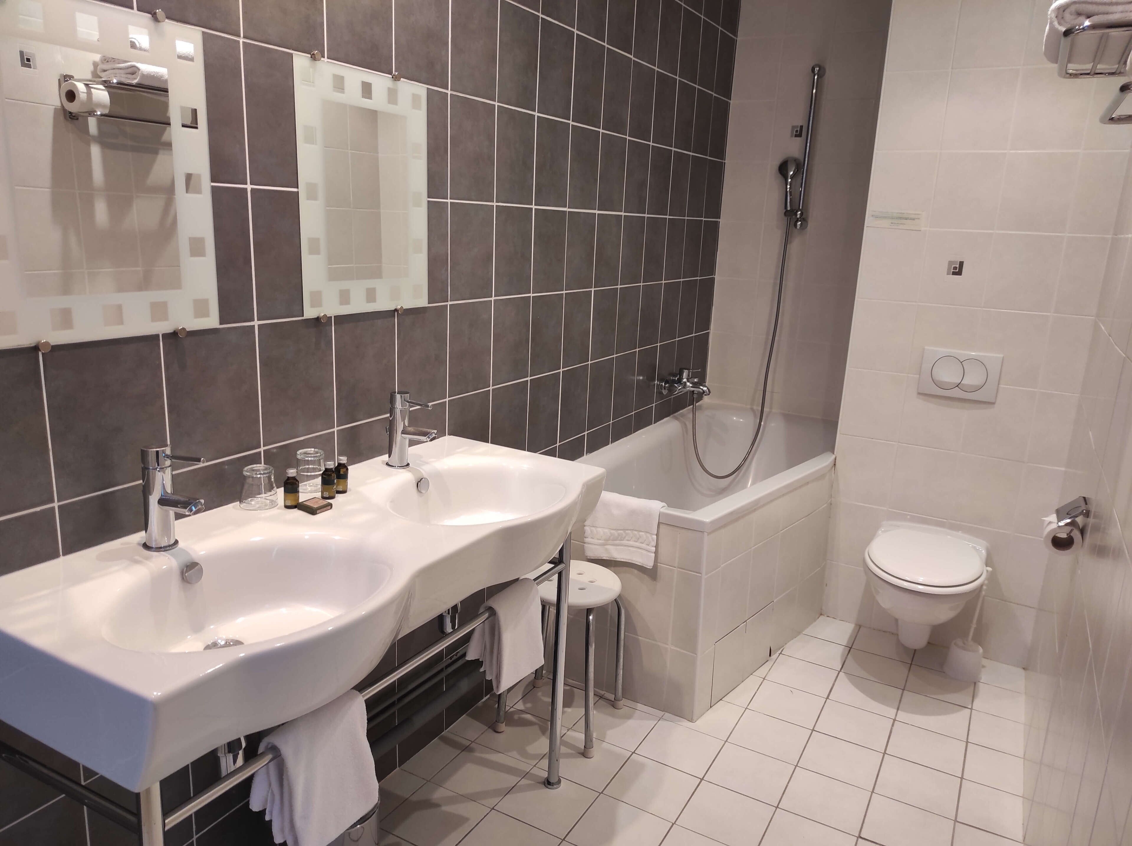 A modern bathroom with two sinks, a bathtub, and a toilet.