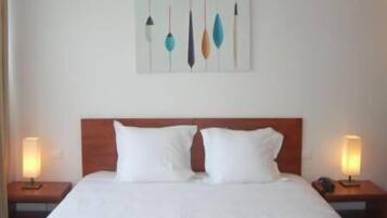 A hotel room with a large bed, two bedside tables, and a wall-mounted artwork.