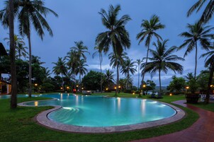 Una piscina rodeada de palmeras y un césped cuidado.