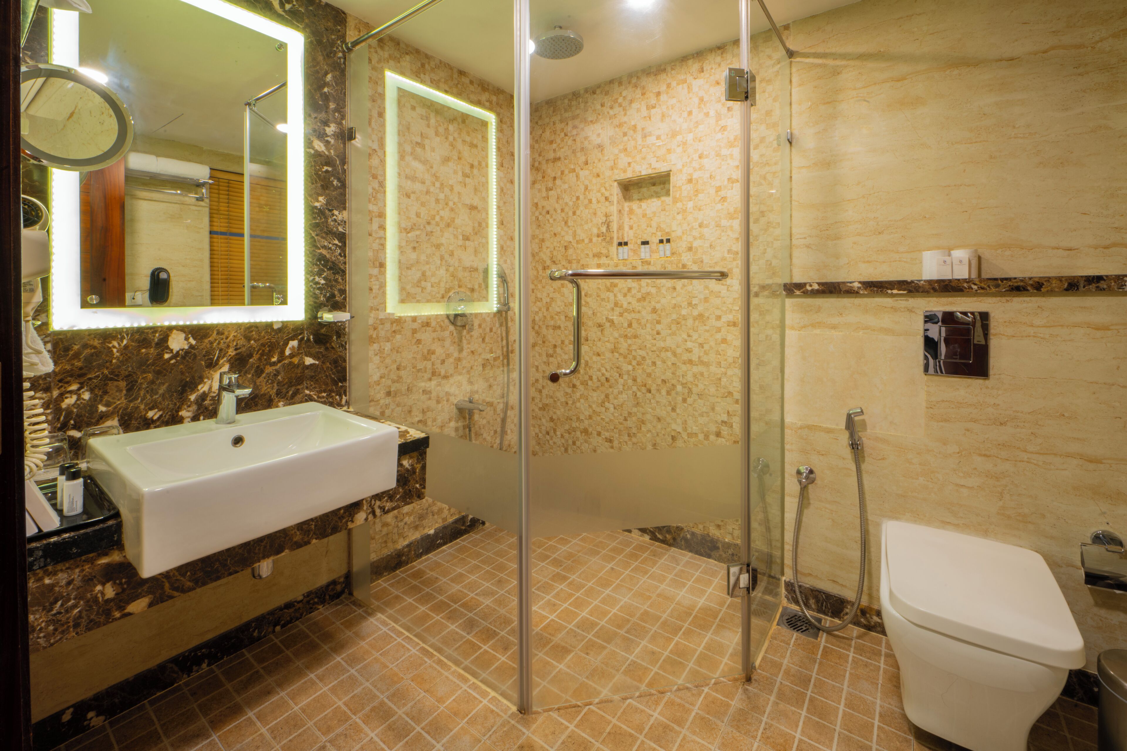 Un bany amb un lavabo, mirall, dutxa i vàter.