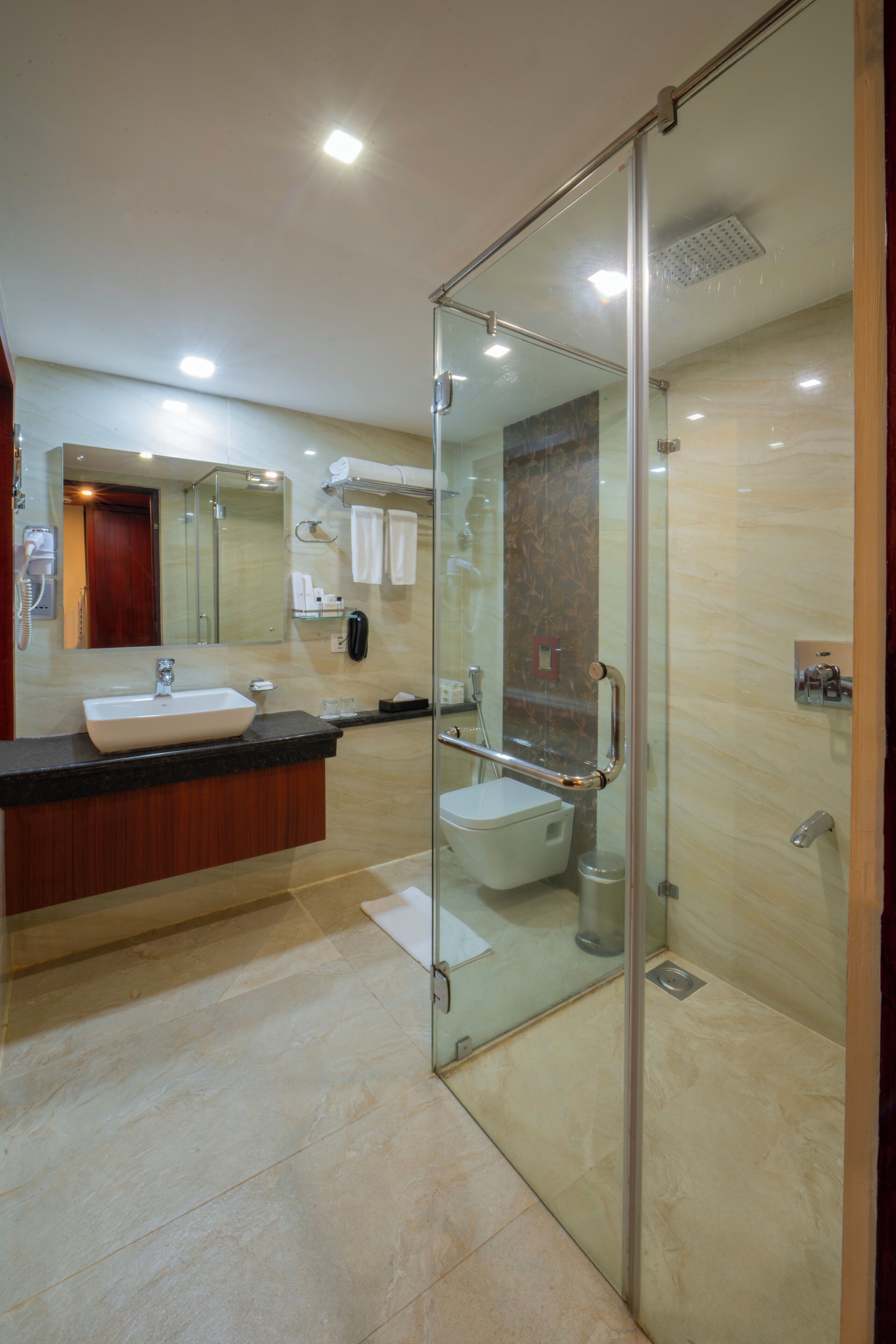 A modern bathroom with a glass-enclosed shower, a sink, and a toilet.