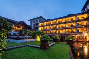 Un hotel de varios pisos con un patio y una piscina reflectante.