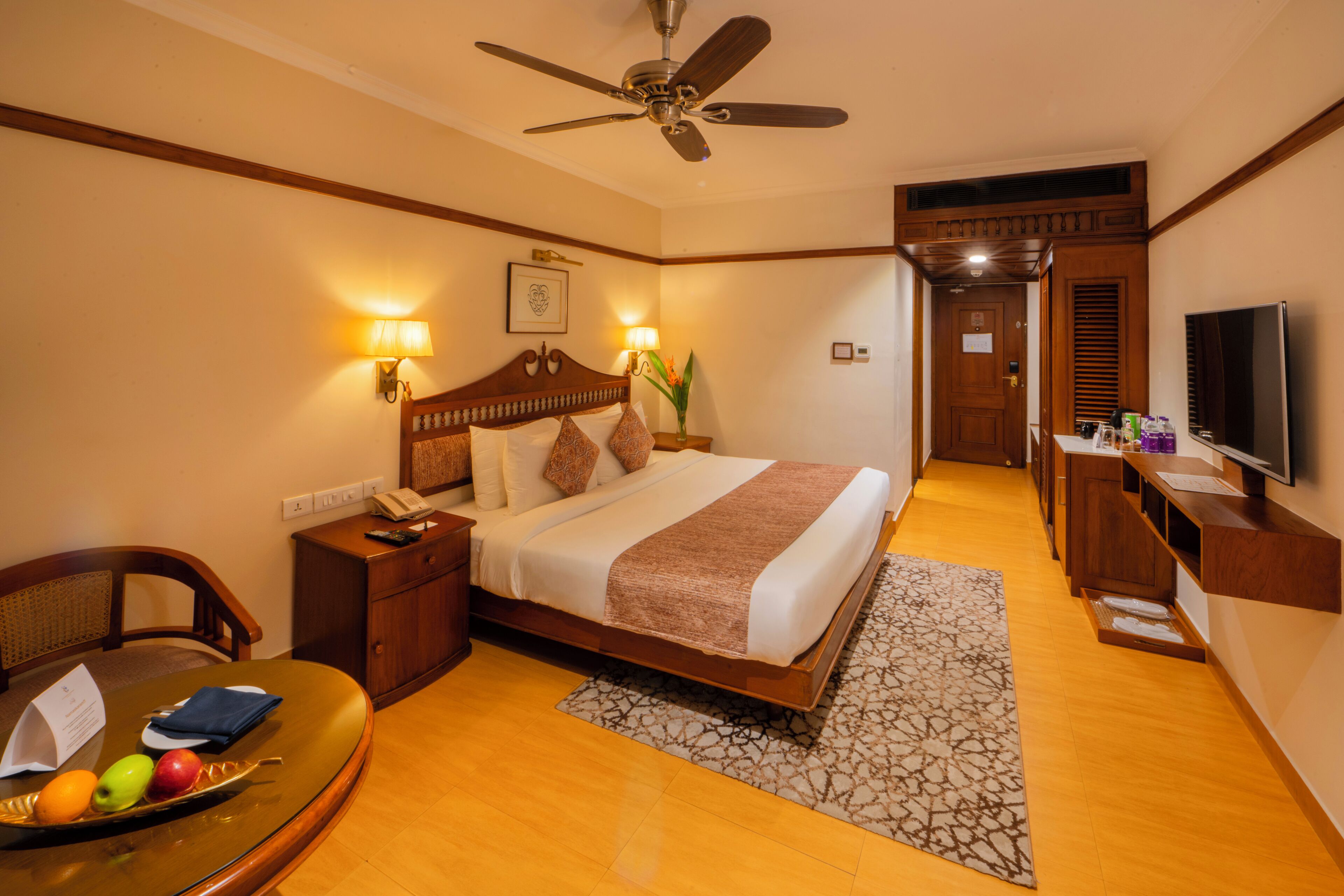 A hotel room with a bed, bedside table, lamp, and a television.