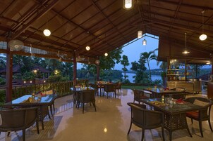 Un área de comedor al aire libre con mesas y sillas, un bar y vista al mar.