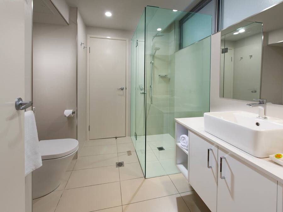 Een moderne badkamer met een douchecabine van glas, een wit toilet en een wastafel met spiegel.