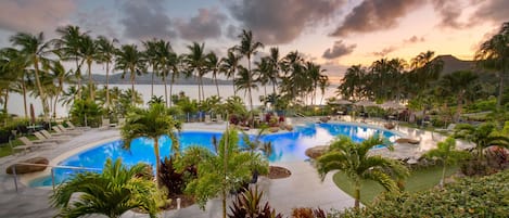 A resort pool surrounded by palm trees and lounge chairs.