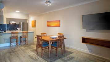 A modern kitchen with a dining area, a flat-screen TV, and artwork on the walls.