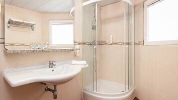Une salle de bain équipée d’un lavabo, d’un miroir, d’un porte-serviettes et d’une douche à parois de verre.