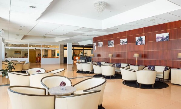 A spacious lobby with modern seating, a reception area, and a wall adorned with photographs.