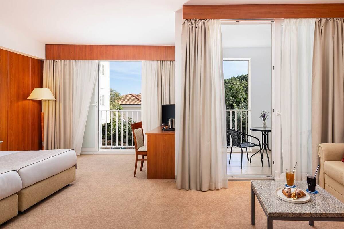 Een hotelkamer met een bed, een bureau, een stoel, een kleintje tafeltje met drankjes en een bank.