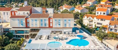 Um hotel com piscina no terraço, várias piscinas e um terraço ajardinado.