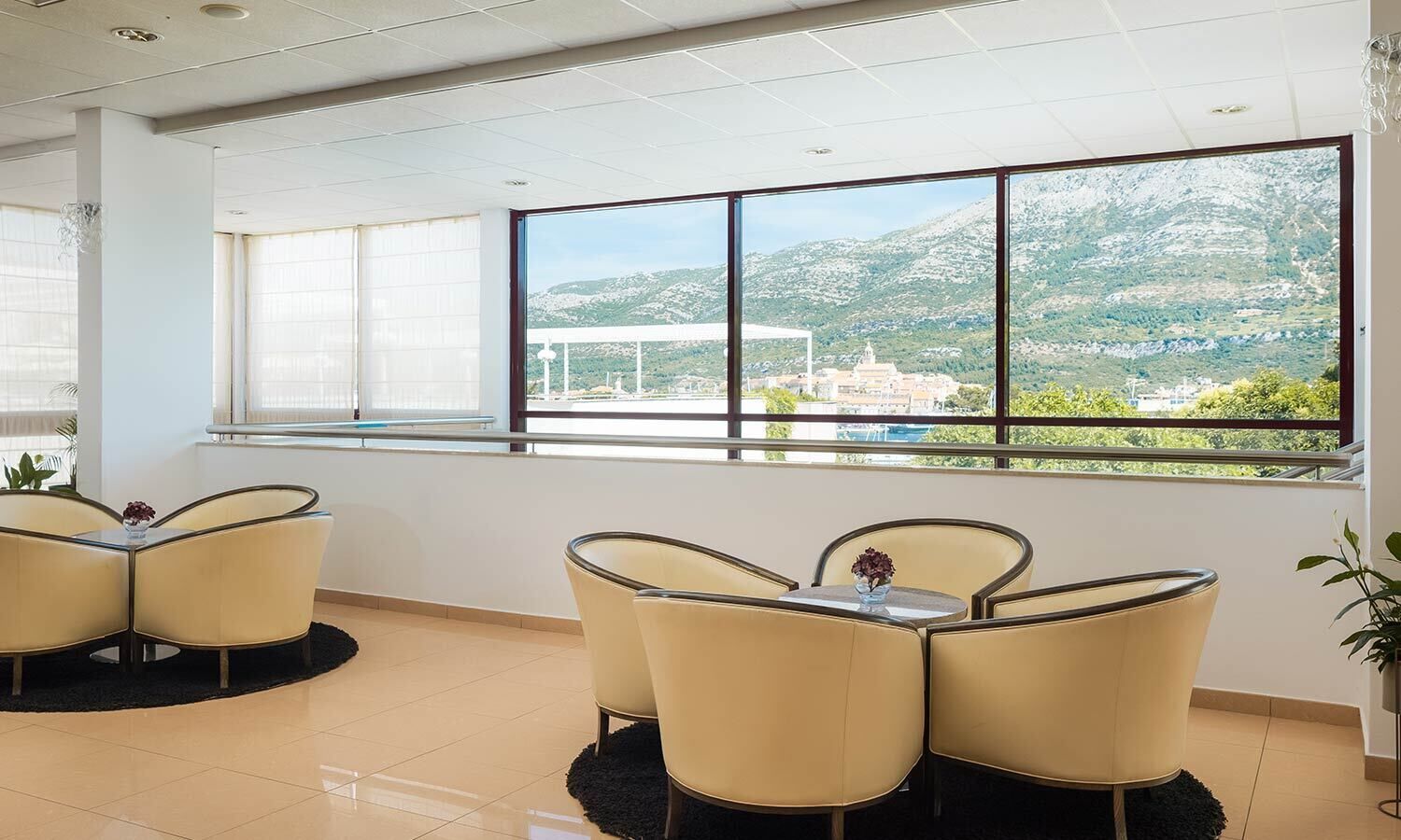 Una sala de conferencias moderna con vistas panorámicas a la montaña, amueblada con sillas y mesas color beige, y grandes ventanales.