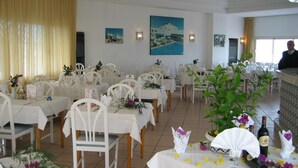 Een restaurant met witte tafels en stoelen, versierd met bloemen en wijnflessen.