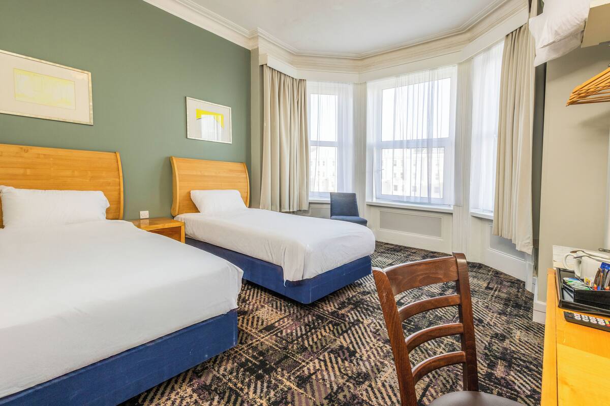 A hotel room with two beds, a desk, and a chair.