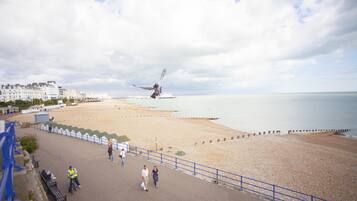 A coastal promenade with benches, a blue railing, and a view of the sea.