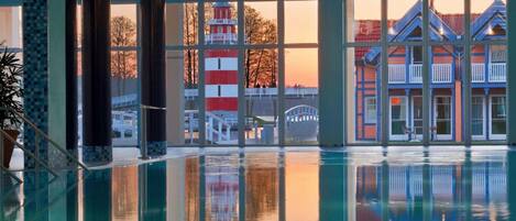 Una piscina con vistas a un faro rojo y blanco y un edificio azul con barandillas blancas.