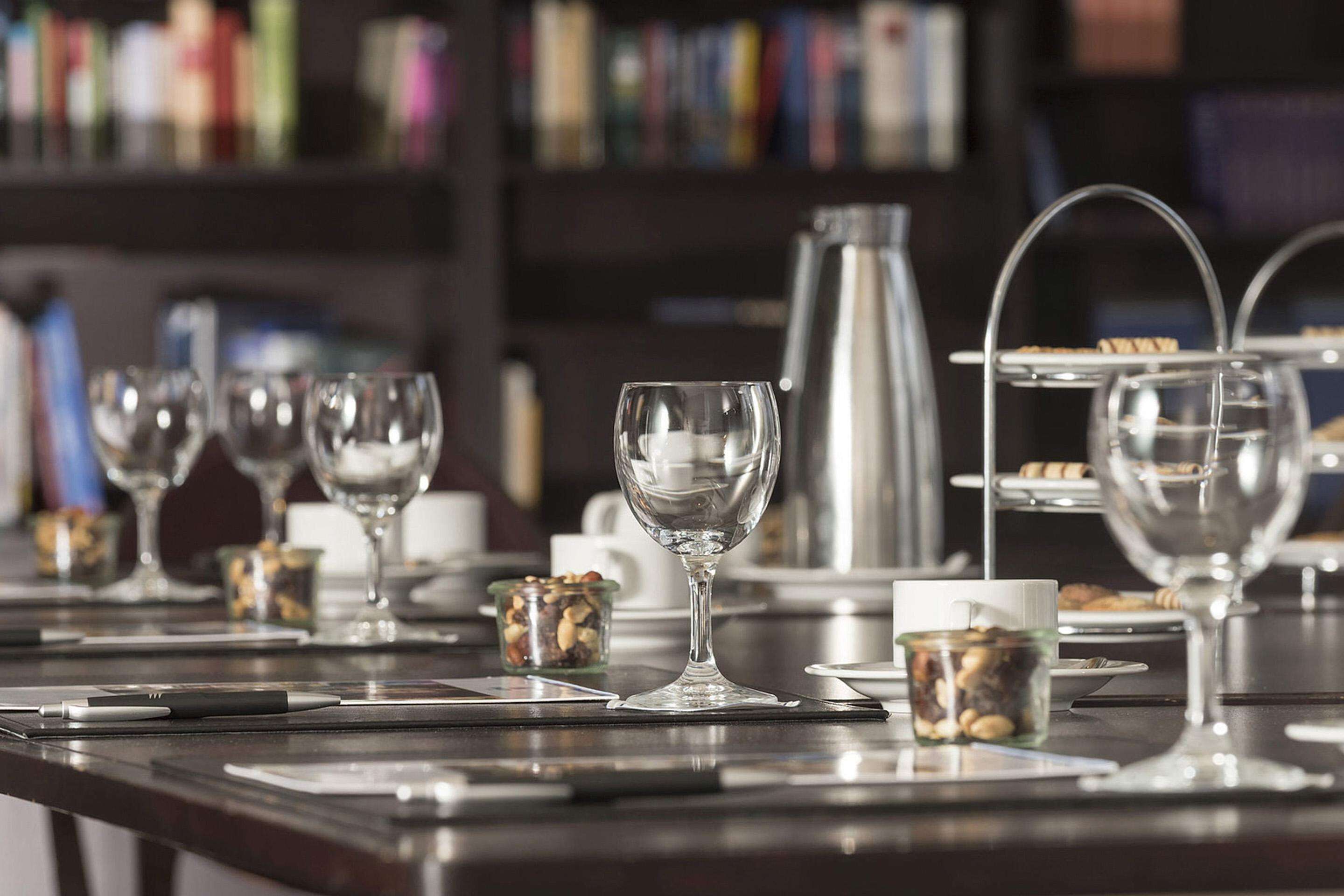 Zona de bar con varios vasos y una máquina de café, con una estantería al fondo.