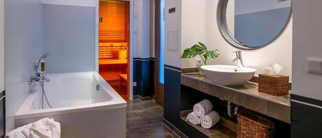 A modern bathroom with a bathtub, a sink, a round mirror, and a towel rack.