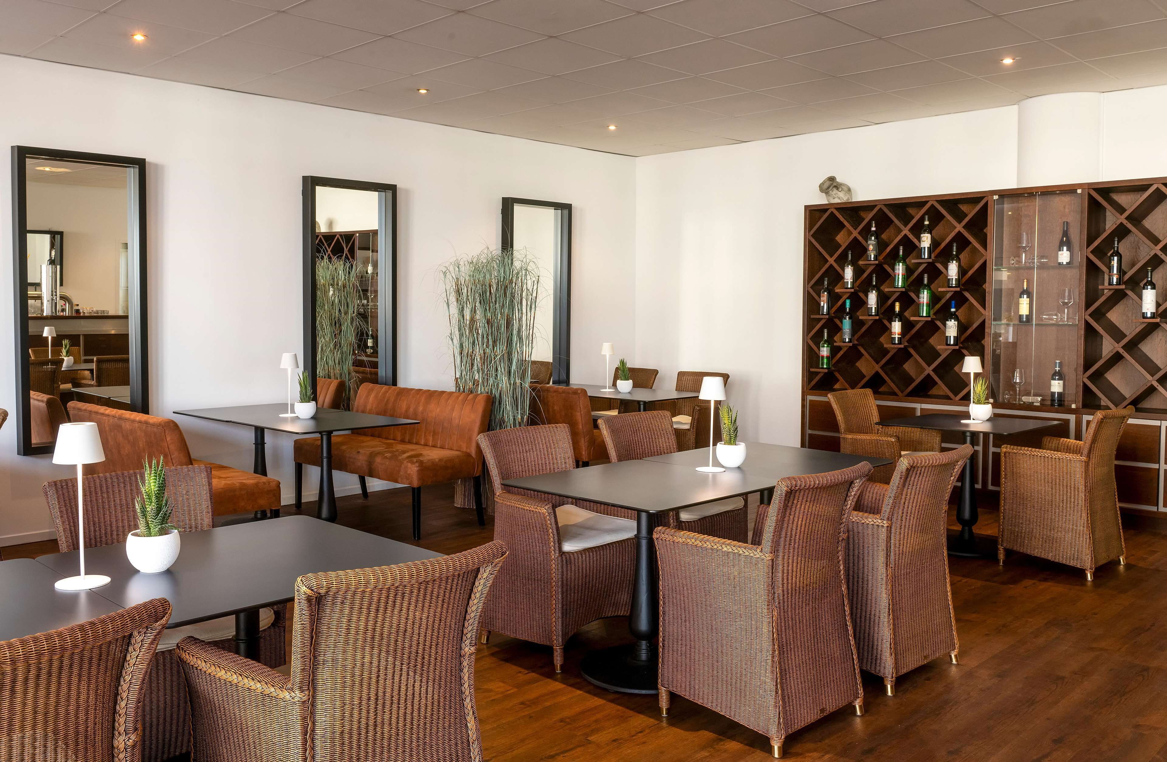 A modern dining area with wicker furniture, a wine rack, and a mirror.