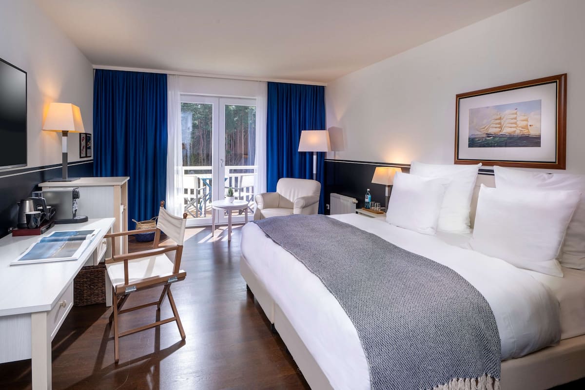 Une chambre d’hôtel avec un lit, un bureau, une chaise et un balcon offrant une vue.