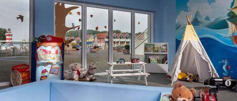 A children's playroom with a ball pit, stuffed animals, a toy car, and a tent.