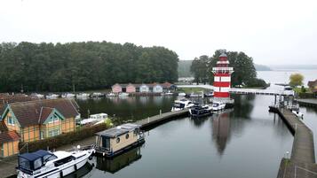 A harbor with boats docked, a lighthouse, and a row of houses along the water.