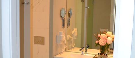 Un baño moderno con un espejo grande, una ducha y un lavabo con tocador.