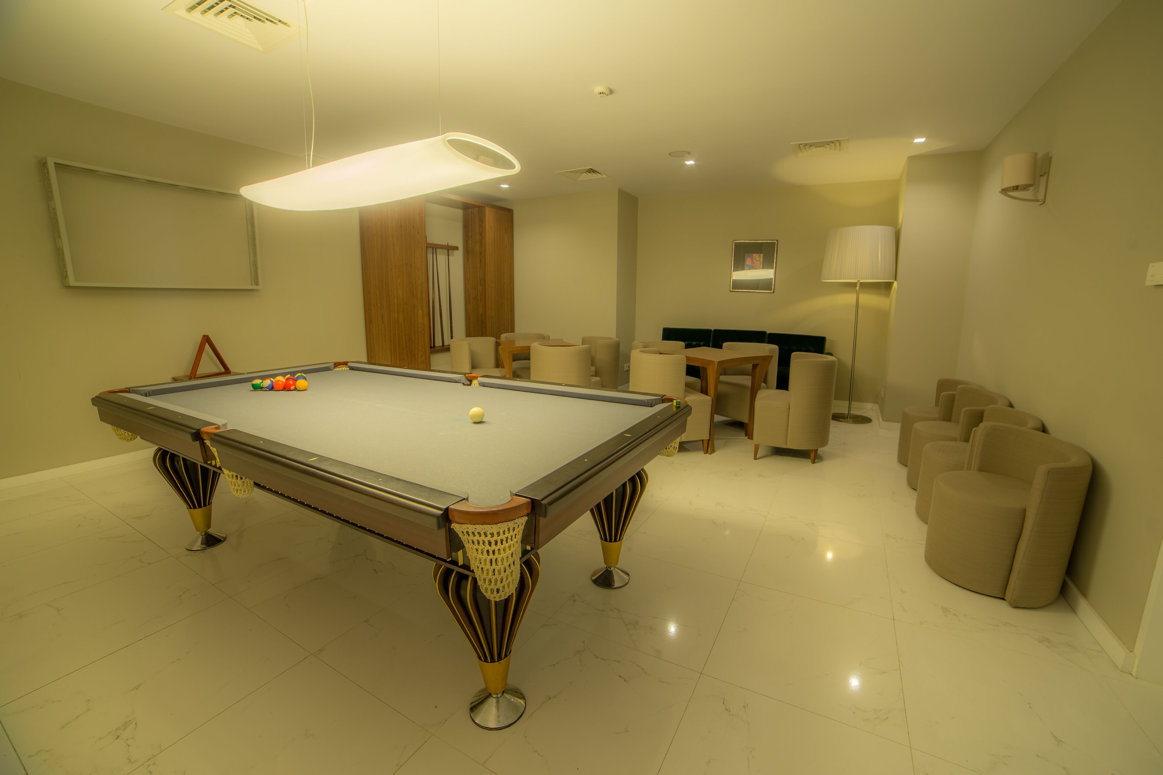 A pool table with a modern design, surrounded by comfortable seating and a well-lit room.