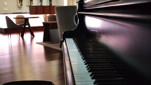 A grand piano in a spacious room with a dining area and modern pendant lighting. - Hotel do Parque (Braga)