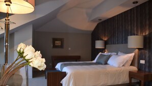 A modern bedroom with a large bed, bedside lamps, and a vase of flowers. - Hotel do Parque (Braga)