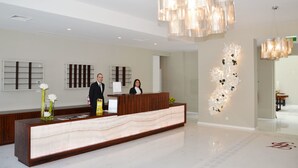 A hotel reception area with a marble reception desk, a modern chandelier, and a wall art installation. - Hotel do Parque (Braga)