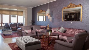 A spacious living room with a large sofa, armchairs, and a coffee table. There is a large mirror on the wall and a chandelier hanging above. - Hotel do Elevador (Braga)