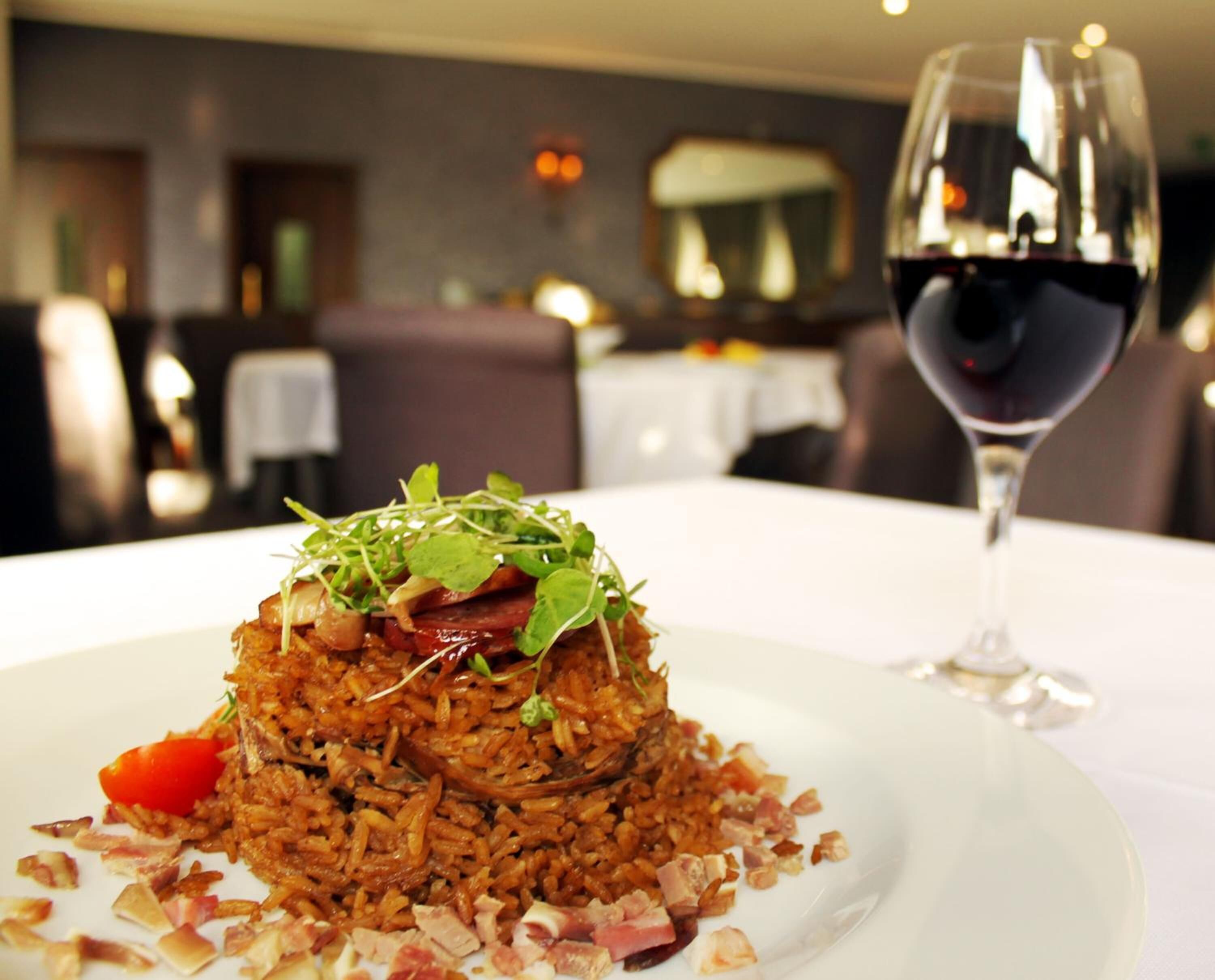 Ein Teller mit Essen und ein Glas Rotwein auf einem Tisch in einem Restaurant.