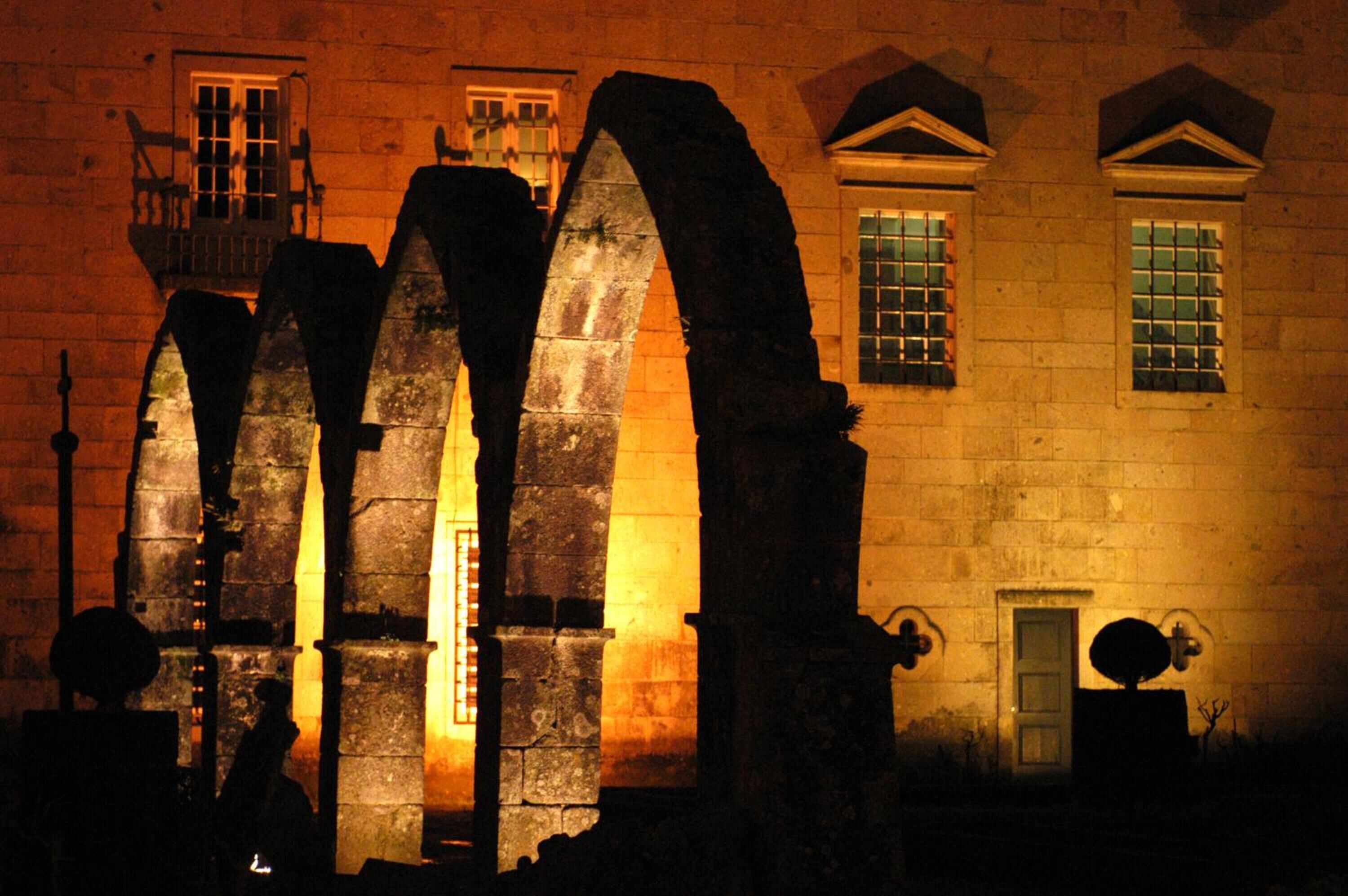 Un edificio de piedra con grandes arcos y una puerta pequeña.