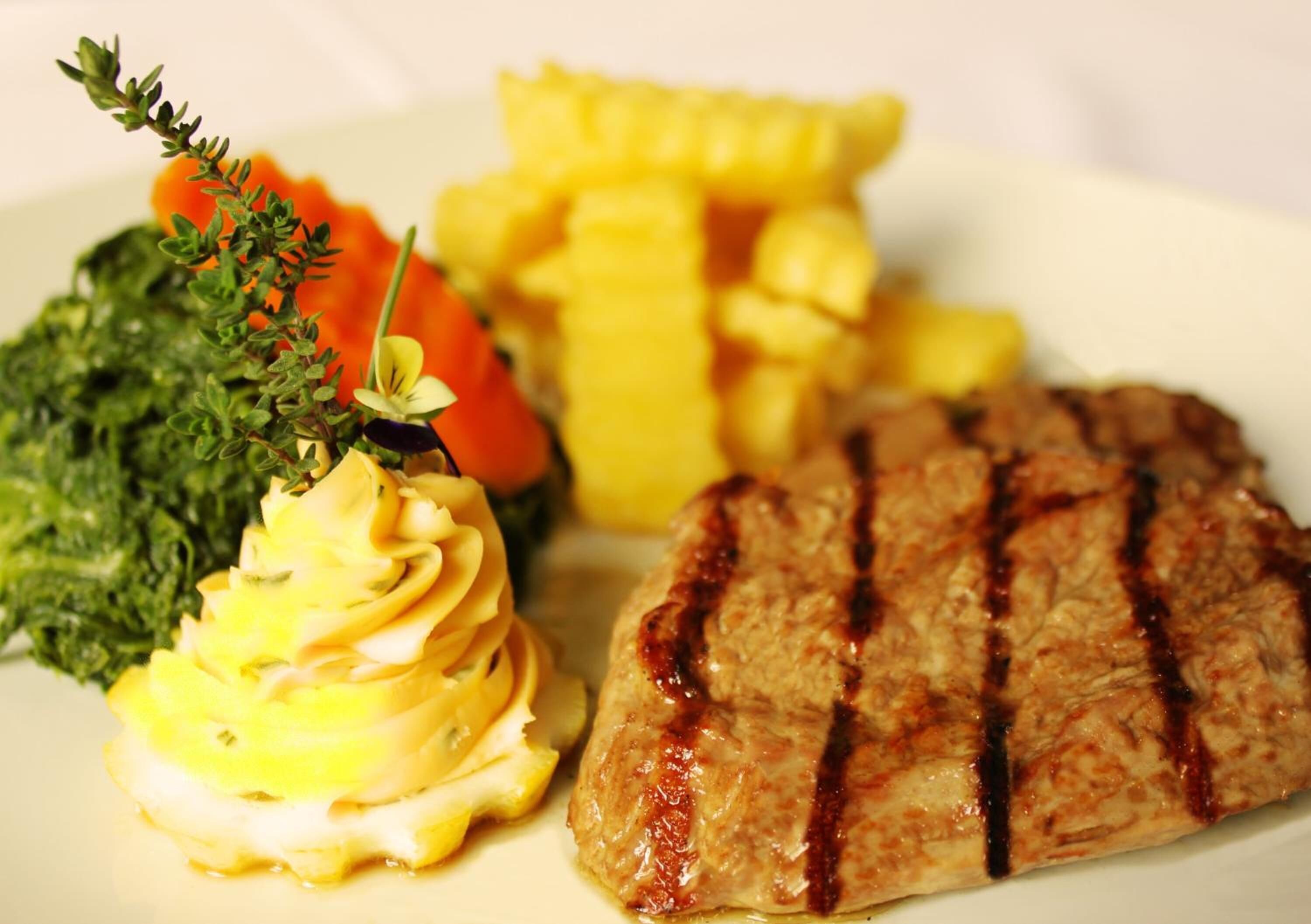 A plate with grilled meat, mashed potatoes, and vegetables.