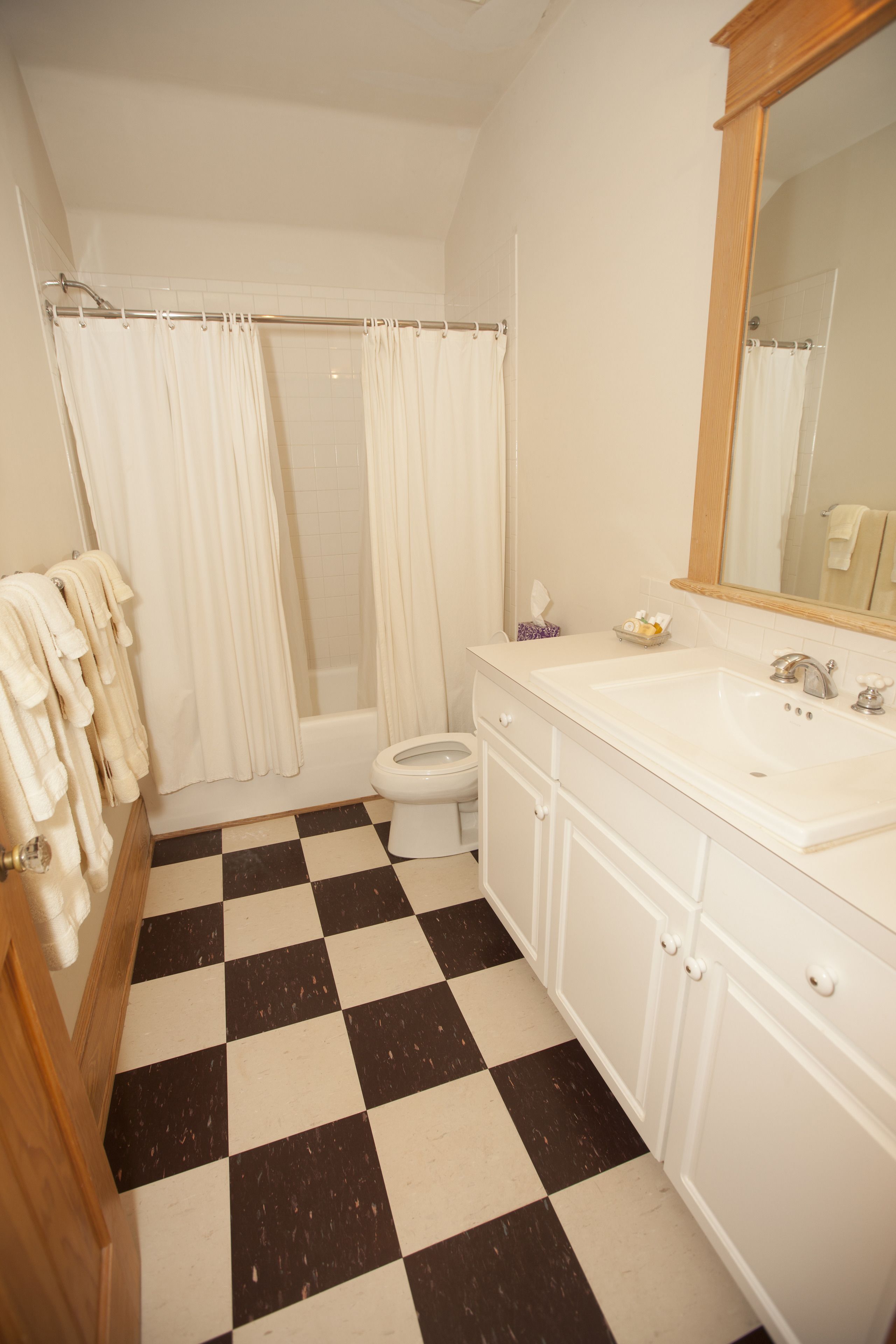 A bathroom with a checkered floor, a bathtub, a toilet, and a sink with a mirror.