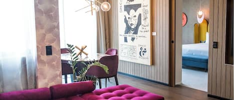 Una sala de estar moderna con un sofá morado, una mesa redonda de centro y un comedor con sillas y una mesa.