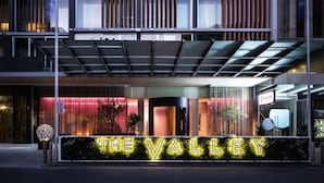 A modern hotel entrance with a prominent illuminated sign reading "THE VALLEY".