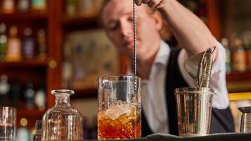 A bartender preparing a drink with a shaker and a glass.