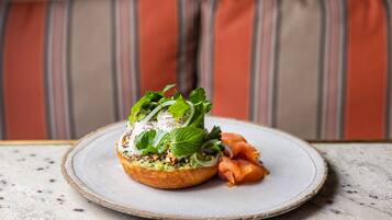 A plate with a sandwich and smoked salmon on a speckled table.