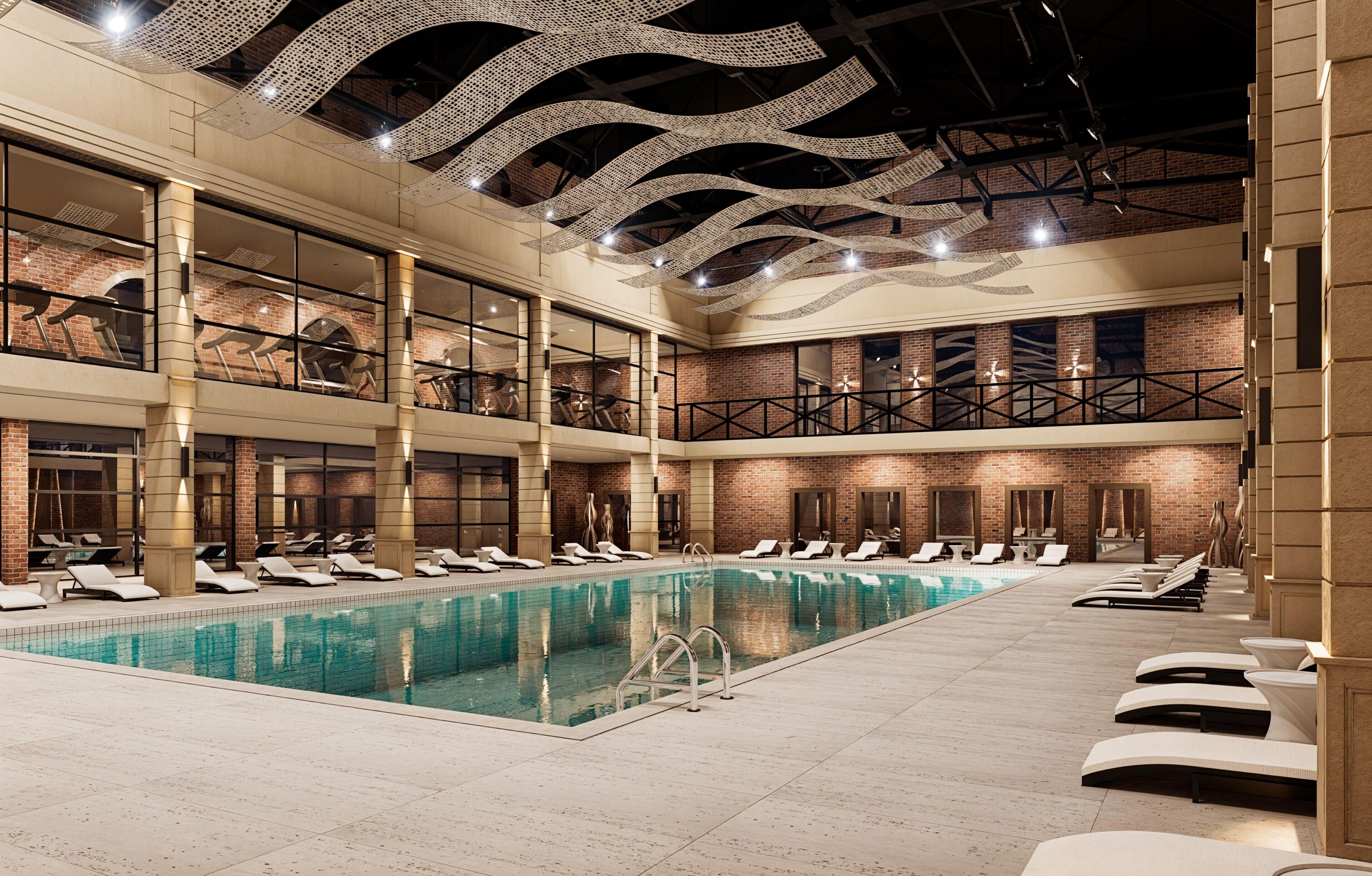 A large indoor swimming pool with multiple levels of balconies and lounge areas.