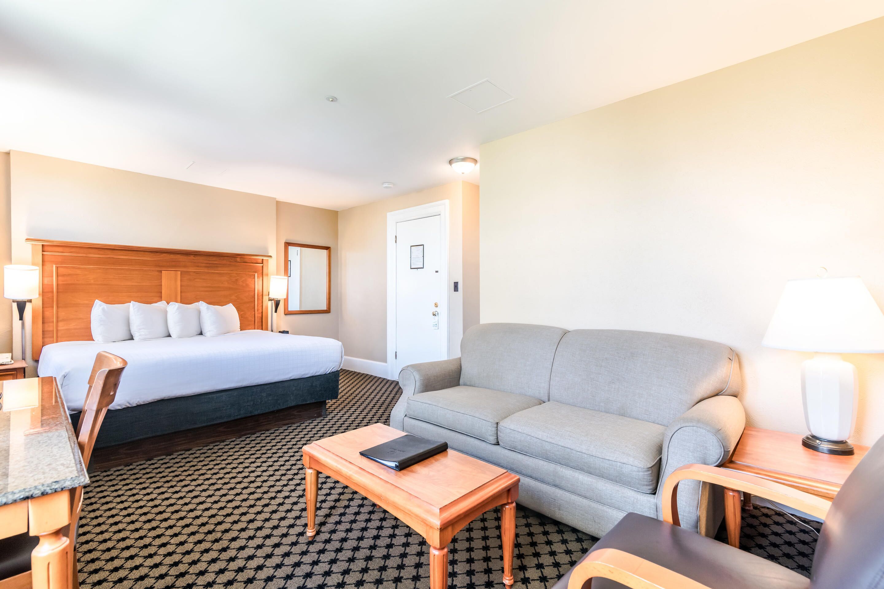 Una habitación de hotel con cama, sofá, mesa y escritorio con silla.