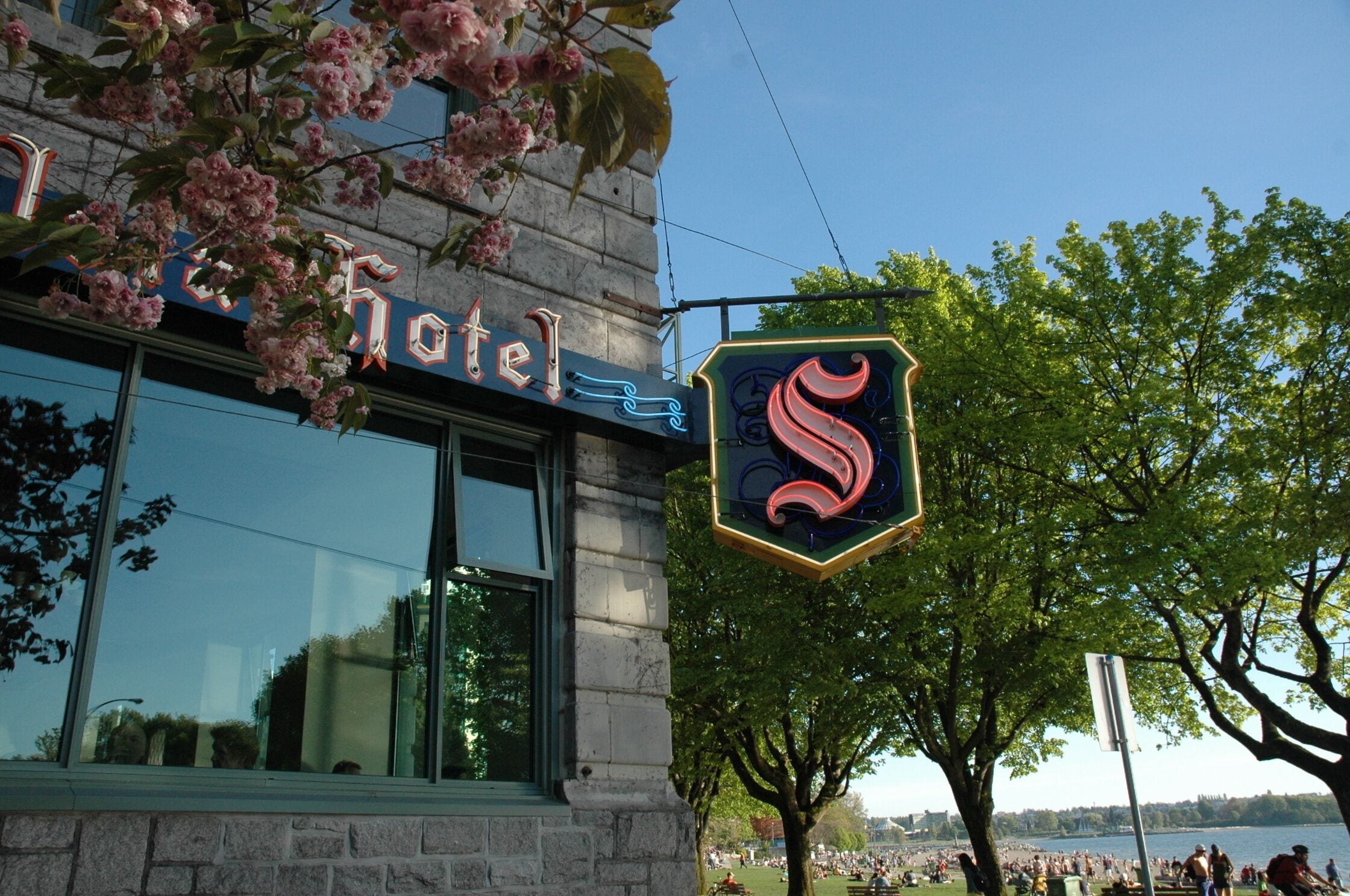 A hotel with a large glass window and a neon sign with a stylized 'S' logo.