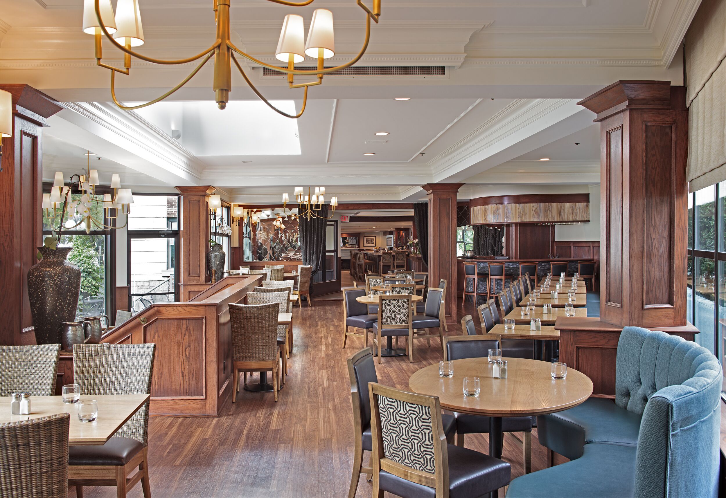 A spacious restaurant with high ceilings, chandeliers, and a variety of seating options including tables and booths.
