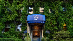 A hotel entrance with a blue awning and a sign reading "HILVIA HOTEL".