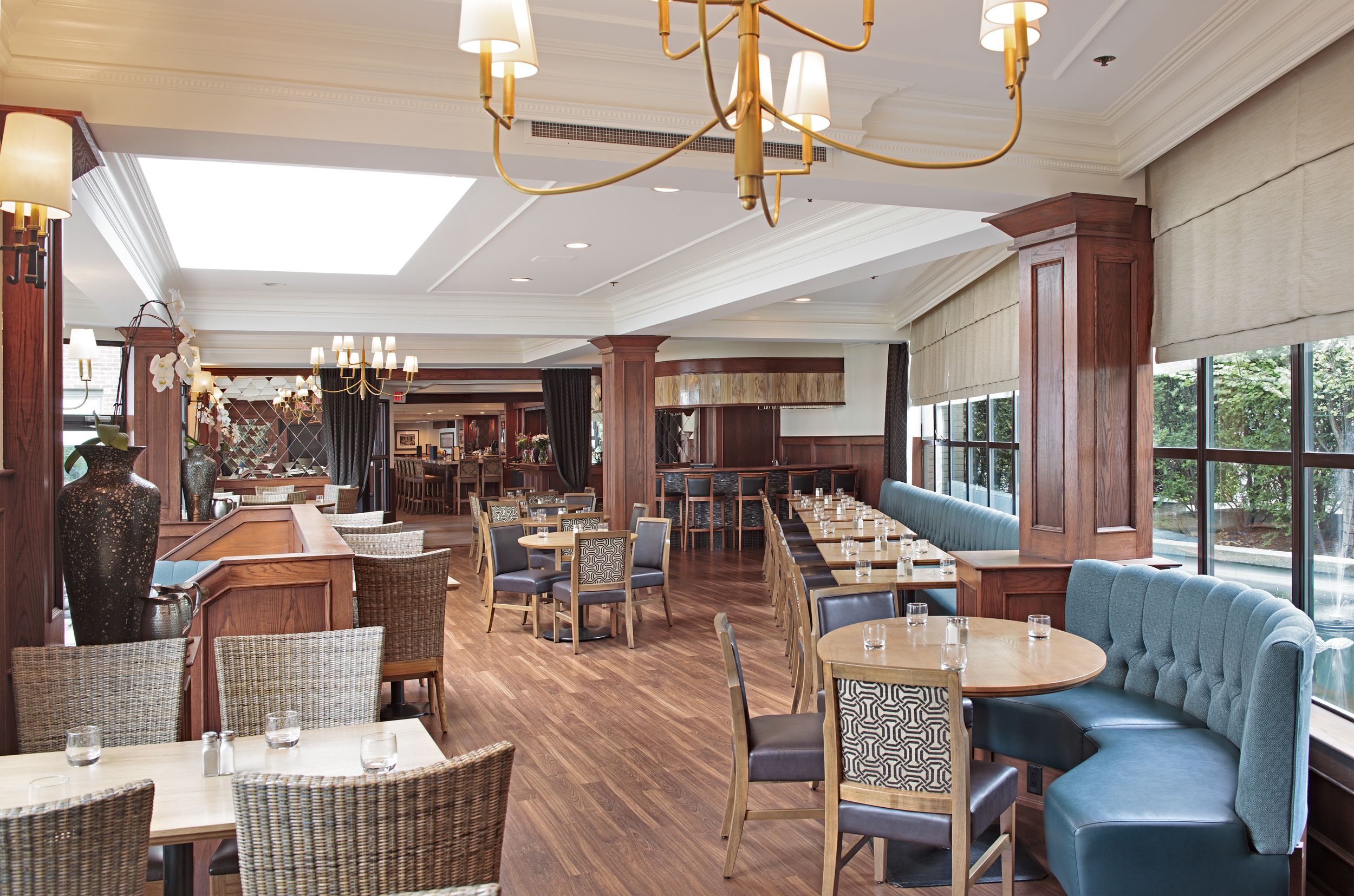A spacious restaurant with high ceilings, chandeliers, and a variety of seating options including tables, booths, and a large blue sofa.