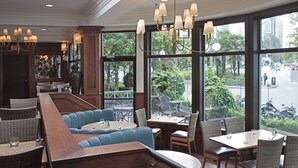 A restaurant with a bar area, seating with blue cushions, and large windows offering a view of the street.