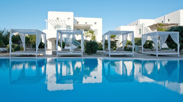 Una piscina al aire libre, sombrillas, sillones reclinables de piscina