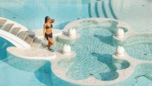 Een zwembadgedeelte met helder water, een ligbed en een jacuzzi.